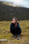 Brunette fille assise tout en regardant la caméra dans les montagnes — Photo de stock