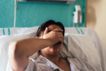 Une jeune femme hospitalisée dans un lit. Des gestes de douleur et de préoccupation. — Photo de stock
