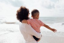 Молода красива матуся грає зі своїм маленьким сином на пляжі — стокове фото