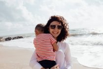 Giovane bella mamma che gioca con il suo bambino figlio sulla spiaggia — Foto stock