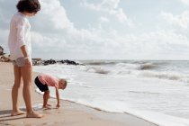 Молодая красивая мамочка играет со своим маленьким сыном на пляже — стоковое фото