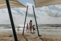 Junge schöne Mama spielt mit ihrem kleinen Sohn und Mädchen am Strand — Stockfoto