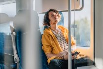 Young man, teenager, traveling in train with headphones, listening to music. Lifestyle shot with copy space. — Stock Photo