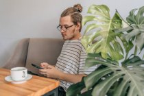 Adolescent jeune homme écrit sms dans le café. Mode de vie tourné avec espace de copie. — Photo de stock