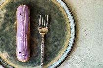 Вкусный французский десерт эклер с лавандой на тарелке — стоковое фото