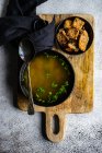 Chicken broth served in a bowl  and set with fresh green onion and fried bread — Stock Photo
