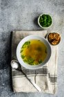 Chicken broth served in a bowl  and set with fresh green onion and fried bread — Stock Photo