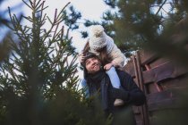 Отец с дочерью на плечах выбирают рождественское дерево на внешнем рынке — стоковое фото
