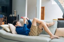 Мальчик играет в онлайн игру на смартфоне дома. — стоковое фото