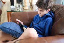 Adolescente chico jugando juego en juego onsole en el sofá en la sala de estar. - foto de stock