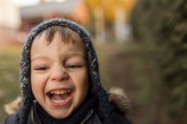 Laughing and running toddler boy in warm clothes in backyard — Stock Photo
