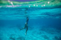 Молодая женщина в синем бикини плавает в воде — стоковое фото