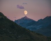 Lune se levant au coucher du soleil alignée avec le sommet de la montagne, Pyrénées. — Photo de stock