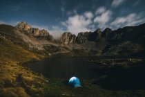 Tente éclairée contre les montagnes accidentées et le lac, Pyrénées. — Photo de stock