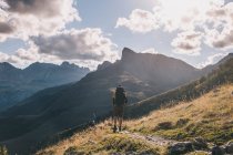 Man hiking with a backpack against high mountain peaks and cloudy sky, Pyrenees, Aragon, Spain — Stock Photo