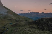Un grupo de jóvenes con carpas mirando atardecer mientras sale la luna, los Pirineos, Aragón, Huesca - foto de stock