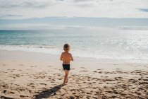 Маленький ребенок играет на песке на пляже — стоковое фото