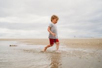 Bambino che gioca sulla sabbia sulla spiaggia — Foto stock
