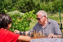 Avô e neto sobre tabuleiro de xadrez — Fotografia de Stock