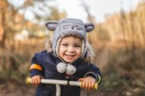Маленький хлопчик надворі в лісі на велосипеді посміхається — стокове фото