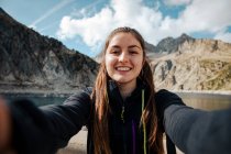 Молодая женщина фотографируется со смартфоном в горах — стоковое фото