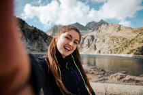 Giovane donna con zaino e bastoncini da trekking in montagna — Foto stock