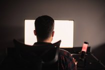 Rückansicht eines Mannes, der am Schreibtisch sitzt und am Computer arbeitet — Stockfoto