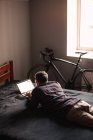 Человек, использующий ноутбук, лежит дома на кровати — стоковое фото