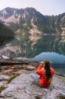 Jovem sentado no lago da montanha, olhando para a distância — Fotografia de Stock
