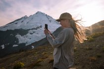 Junge Frau mit Rucksack und Smartphone am Berg — Stockfoto