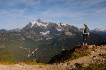 Ein Mann in weißer Jacke und Rucksack wandert in den Bergen — Stockfoto