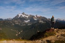 Excursionista con una mochila y una montaña en el fondo - foto de stock