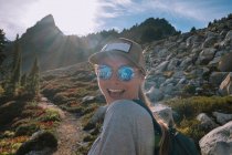 Mujer con mochila y gafas de sol en el fondo de las montañas - foto de stock