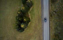 Vista dall'alto della guida in auto su strada asfaltata che corre tra foresta e campo in terreno rurale in Islanda — Foto stock