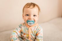 Portrait of infant boy smiling with dummy — Stock Photo