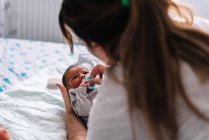 Mãe colocando chupeta para seu bebê na cama. — Fotografia de Stock