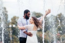 Le beau jeune couple de personnes diverses danse ensemble dans une fontaine de la ville — Photo de stock