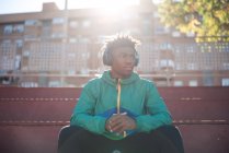 Junger Schwarzer entspannt sich beim Musikhören in der Stadt. — Stockfoto