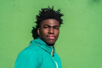 Retrato de niño negro serio sobre fondo de pared verde. - foto de stock