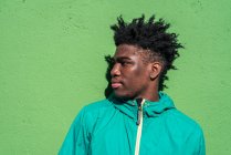 Portrait of serious black boy on green wall background. — Stock Photo