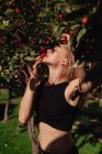 Красива молода жінка з червоним яблуком в саду — стокове фото