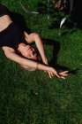 Красива молода жінка лежить на зеленій траві в парку — стокове фото