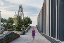 Giovane donna con zaino che cammina sul ponte — Foto stock