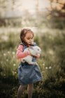 Chica joven sosteniendo un conejo con un fondo borroso. - foto de stock