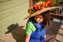 Kleines Mädchen mit Hut und einem Korb voller Blumen — Stockfoto