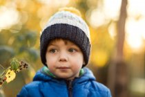 Portrait of small boy in garden in blue jacket during fall — Stock Photo