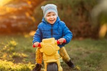 Маленький хлопчик з блакитними очима та сині куртки на пластиковій іграшці — стокове фото