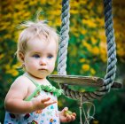 Mignon bébé fille 3-4 ans dans le jardin joue une balançoire rustique — Photo de stock