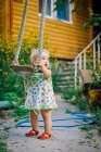 Симпатичная девочка 3-4 лет в саду играет на шуршащих качелях — стоковое фото