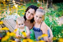 Мама в саду і дві дочки — стокове фото